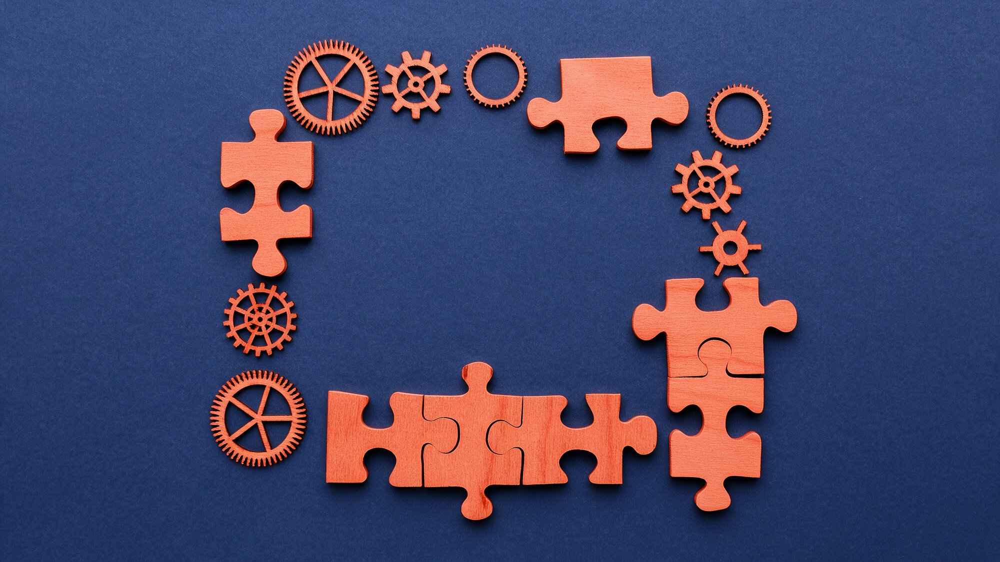 Orange puzzle pieces and gears outlining a rectangular boardroom table, symbolizing a board skills analysis of directors’ collective expertise and capabilities.